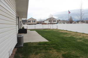View of yard with a fenced backyard, central air condition unit, a residential view, and a patio area
