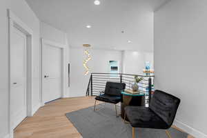 Sitting room featuring light wood finished floors, baseboards, an upstairs landing, and recessed lighting