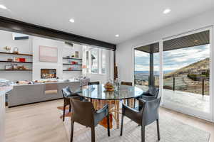 Dining room with a mountain view, recessed lighting, a glass covered fireplace, and light wood-style floors