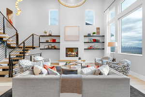 Living area featuring baseboards, a towering ceiling, wood finished floors, and stairway