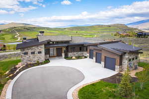 View of front of home featuring a standing seam roof, a mountain view, stone siding, and curved driveway