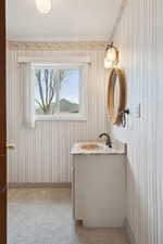 Bathroom with wallpapered walls and vanity