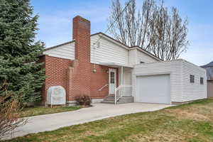 View of front facade with a front yard, driveway, a garage, and a chimney