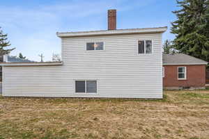 Back of house with a lawn and a chimney