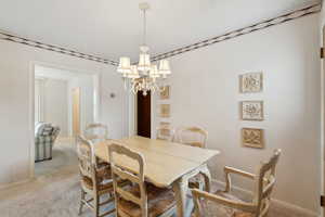 Dining area featuring a notable chandelier, baseboards, and light colored carpet