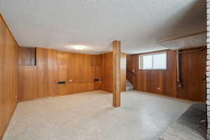 Below grade area featuring baseboards, wood walls, stairway, and a textured ceiling