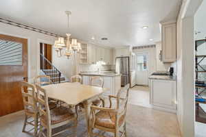 Dining room with light colored carpet, a notable chandelier, stairs, and recessed lighting