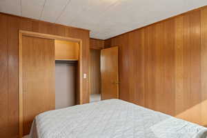 Bedroom featuring a closet and wooden walls