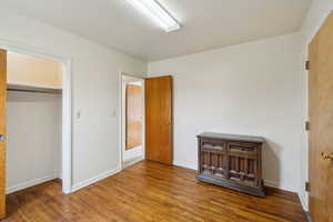Unfurnished bedroom featuring baseboards, wood finished floors, and a closet