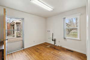 Unfurnished room with wood finished floors, baseboards, and visible vents
