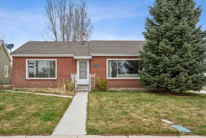 Single story home with brick siding, a shingled roof, and a front yard