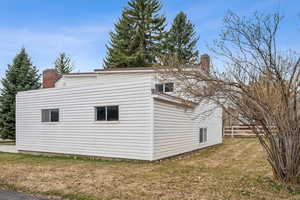 View of home's exterior featuring a lawn, fence, and a chimney