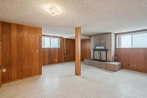 Basement with a fireplace, wood walls, and a textured ceiling