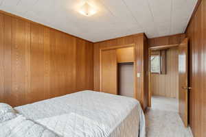 Bedroom with a closet, wooden walls, and carpet