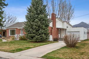View of front facade with brick siding, a garage, a front lawn, and concrete driveway