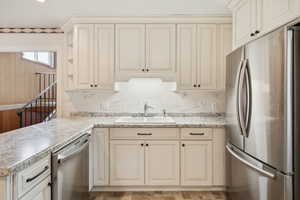 Kitchen featuring backsplash, cream cabinetry, a sink, and appliances with stainless steel finishes