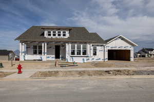 Property in mid-construction with a garage, a shingled roof, and covered porch