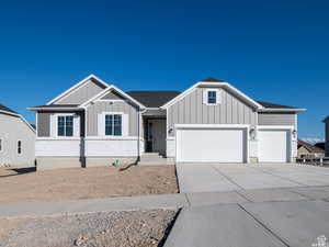 View of front facade featuring board and batten siding, driveway, and an attached garage