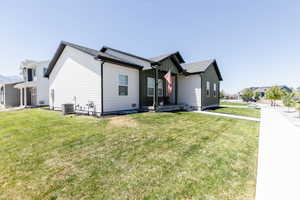 View of front of property with board and batten siding, a front lawn, and a shingled roof