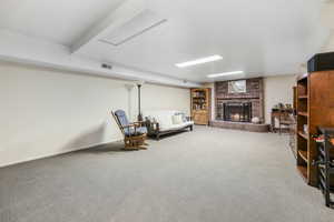 Living area featuring a brick fireplace, carpet floors, baseboards, and visible vents