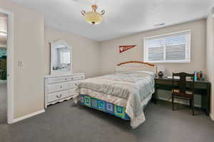 Bedroom featuring dark carpet, baseboards, a textured ceiling, and visible vents