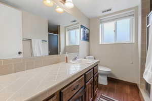 Full bath featuring toilet, baseboards, a shower stall, visible vents, and wood finished floors
