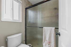 Full bath featuring a stall shower and toilet