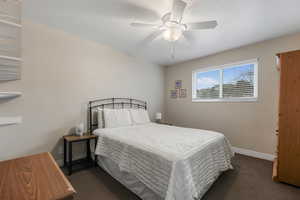 Bedroom featuring baseboards, dark carpet, and ceiling fan