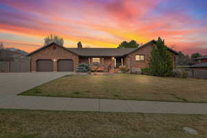 View of front of home with a chimney, fence, brick siding, a front lawn, and a garage