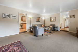 Carpeted living room with baseboards and crown molding