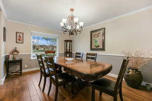 Dining room featuring crown molding, wood finished floors, and an inviting chandelier