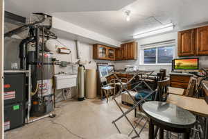 Kitchen with concrete floors, a textured ceiling, secured water heater, brown cabinetry, and glass insert cabinets