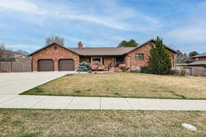 Ranch-style house with fence, driveway, a front yard, a garage, and a chimney