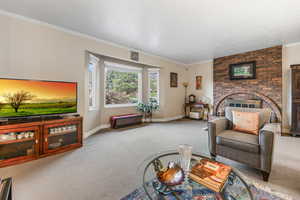 Living room featuring carpet floors, ornamental molding, baseboards, and a fireplace