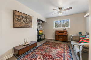 Living room with carpet floors, baseboards, and ceiling fan