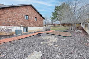 View of side of home featuring brick siding, central air condition unit, and a fenced backyard