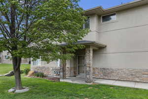 Entrance to property featuring stone siding, a yard, and stucco siding