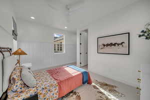 Carpeted bedroom featuring a ceiling fan and a wainscoted wall