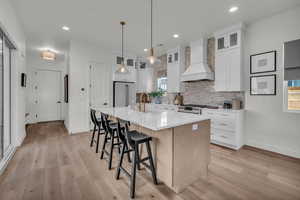 Kitchen featuring stainless steel appliances, a sink, baseboards, a kitchen bar, and custom range hood