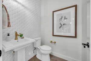Half bath featuring toilet, wood finished floors, and baseboards