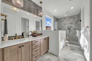 Full bath featuring a tub to relax in, marble finish floor, double vanity, a marble finish shower, and a sink