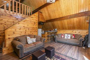 Living area featuring wooden ceiling, lofted ceiling with beams, wood walls, and wood finished floors