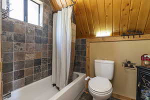 Full bathroom featuring toilet and shower / bathtub combination with curtain