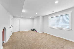 Basement with light carpet, baseboards, recessed lighting, and a textured ceiling