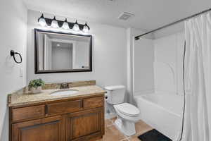 Full bathroom with tile patterned floors, toilet, vanity, a textured ceiling, and visible vents