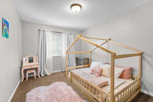 Bedroom with baseboards, carpet flooring, and a textured ceiling
