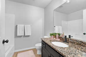 Full bath featuring baseboards, visible vents, toilet, and vanity