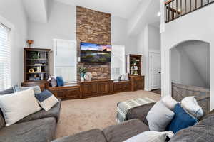 Carpeted living room featuring arched walkways and high vaulted ceiling