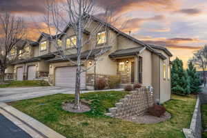 View of front of home featuring driveway, stone siding, an attached garage, and stucco siding