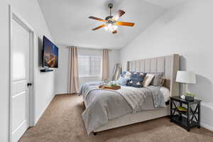 Bedroom featuring carpet floors, baseboards, lofted ceiling, and ceiling fan